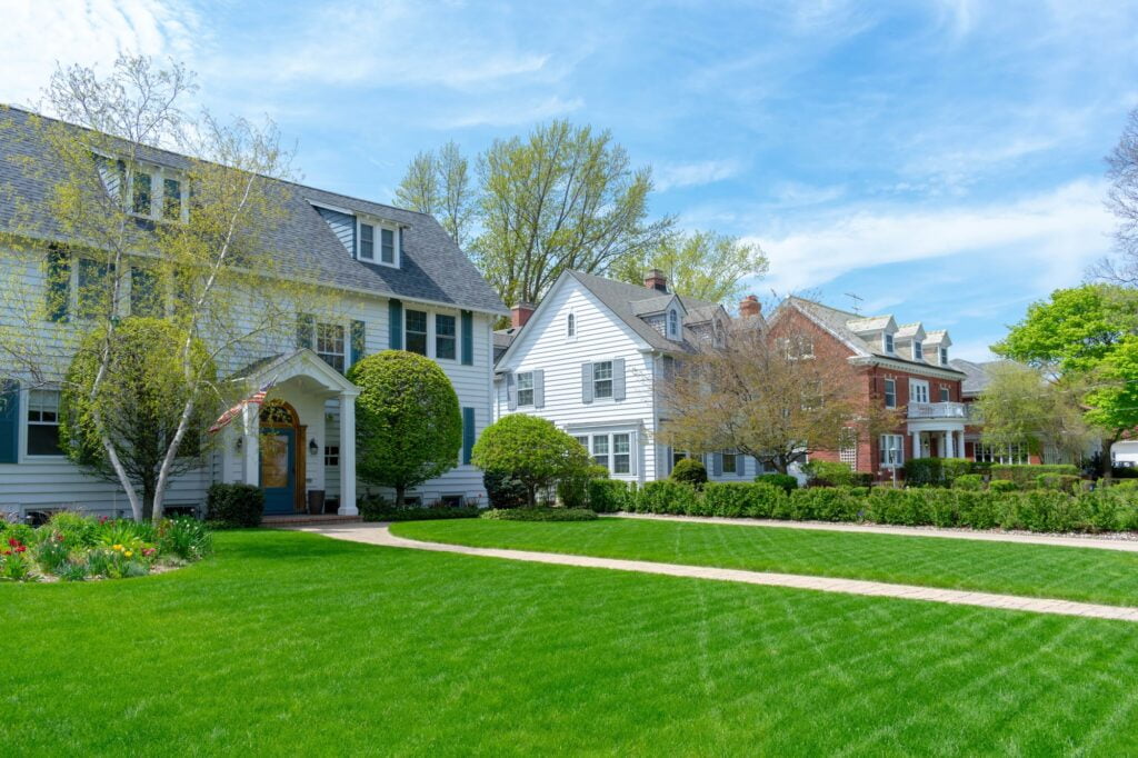 Row of traditional suburban homes with lush green front lawns in nice residential neighborhood